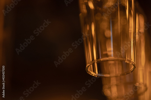 Glass goblets for wine, champagne, alcoholic drinks hang upside down above the bar. Warm orange evening light, Macro, place for text