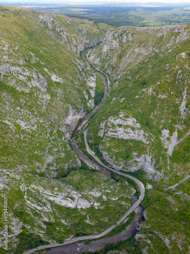 Aerial drone vertical panorama above Sohodol Gorges. A road wides along the river through its tight rocky canyon. Carpathia, Romania. 