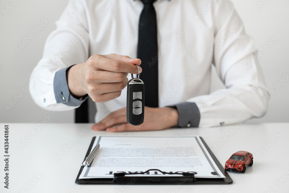 Auto sales agent holding a key in the office.