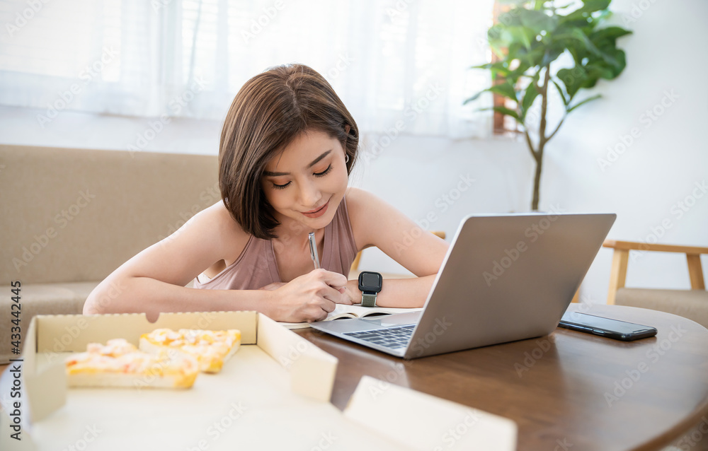 Portrait of happy asian woman working on laptop computer, have lunch break eating pizza in sofa living room using internet. Delivery, work from home quarantine sme new normal copy space background Portrait of happy asian woman working on laptop computer, have lunch break eating pizza in sofa living room using internet. Delivery, work from home quarantine sme new normal copy space background