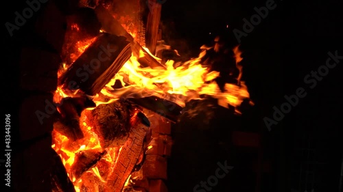 A large fire made of wood in a special place for a fire lined with bricks at night. Vertical Video. Slow motion