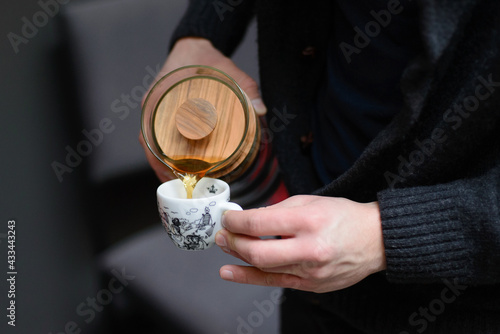 Man puring filtered coffee into small cup