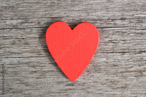 A red wooden heart lies on a wooden background.Background for greeting cards for Valentine's Day, Birthday, Mother's Day.Top view.Flat styling style.Copyspace