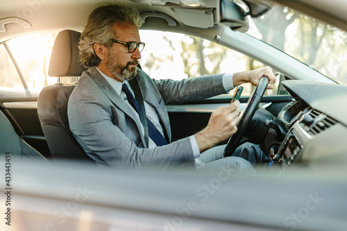 Businessman texting on his mobile phone while driving. © Nebojsa