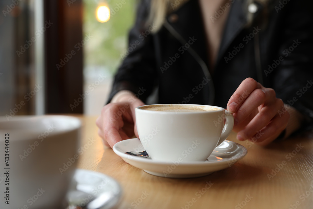 Young woman with cup of coffee at table in morning, closeup - obrazy, fototapety, plakaty 