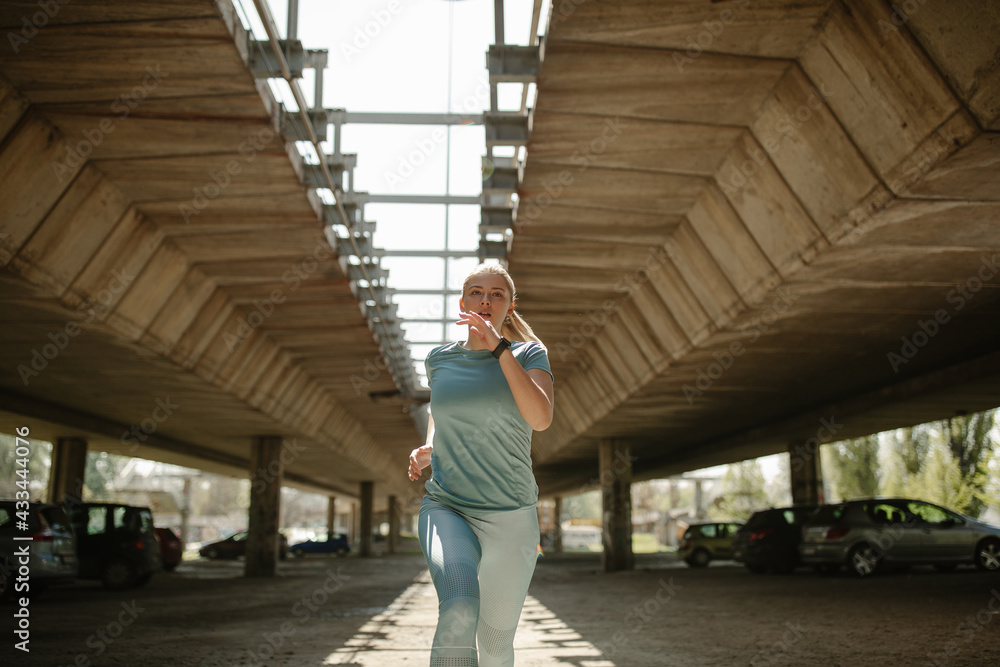 Beautiful woman running under the bridge on the morning.