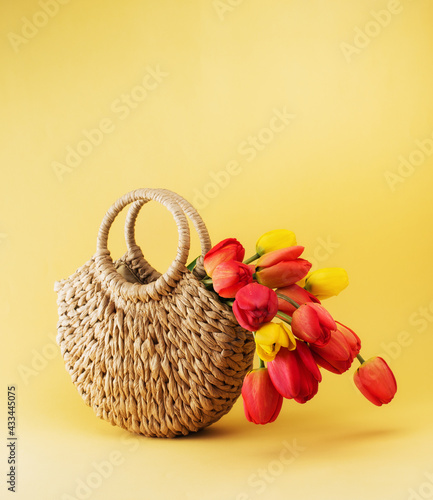 Beautiful flowers tulips in a basket on a yellow background with copy space