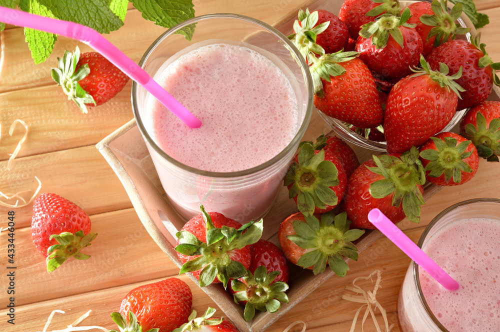 Glasses with strawberry smoothie with milk on wooden table Glasses with strawberry smoothie with milk on wooden table