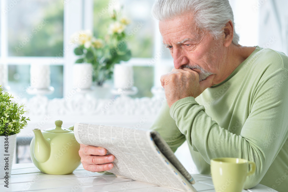 Emotional senior man reading newspaper Emotional senior man reading newspaper