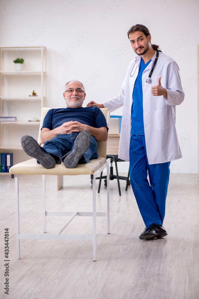 Old male patient visiting young male doctor chiropractor Old male patient visiting young male doctor chiropractor