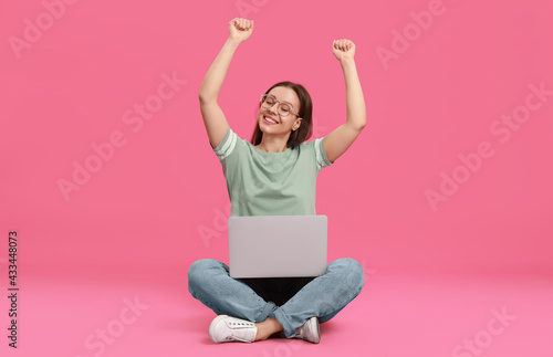 Young woman with modern laptop on pink background © New Africa