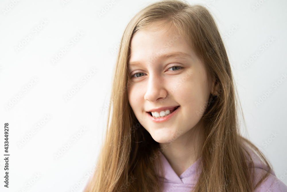 portrait of beautiful teenage girl with long hair in purple huddy standing against white wall
