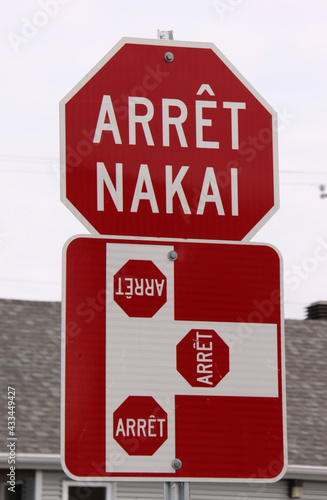 red and white stop sign with stop text in French and local native canadian Innu language (arrêt = stop, nakai = stop) photo