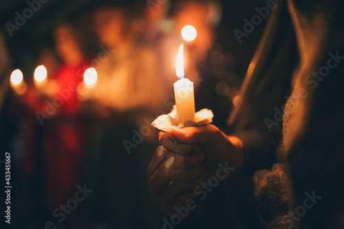 a girl holds a lighted candle in her hands, a religious tradition, a symbol of the Christian faith, a wax candle burns with an even flame, blow out a candle, a smoke from an extinguished wick