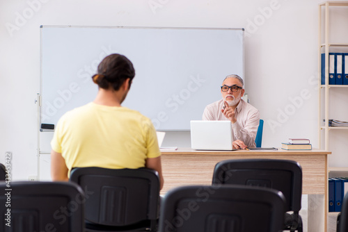 Young male student and experienced teacher in pandemic concept