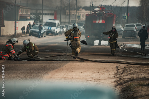 a team of rescuers extinguish a fire in the house. firefighters pour water on the raging flames. smoke and smog from the burning building © evgavrilov