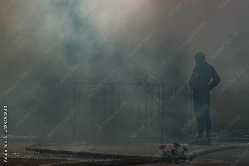Obraz premium the fire destroys the building. the fire brigade pours water on the burning house. people are suffocating from the smoke and smog from the fire. fire victims