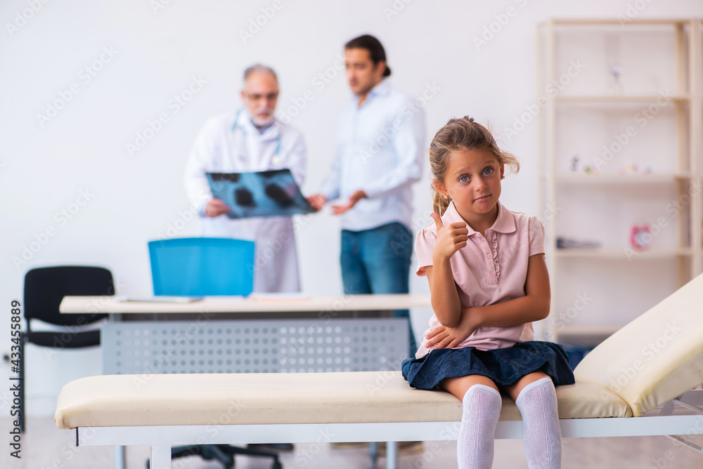 Small girl with her father visiting old male doctor radiologist Small girl with her father visiting old male doctor radiologist