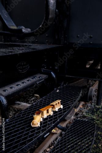 wooden toy train on steel steps of historic big train