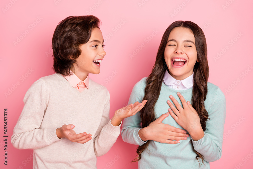 Portrait of attractive trendy cheerful kids boy sharing funny joke to girl laughing having fun isolated over pink pastel color background - obrazy, fototapety, plakaty 