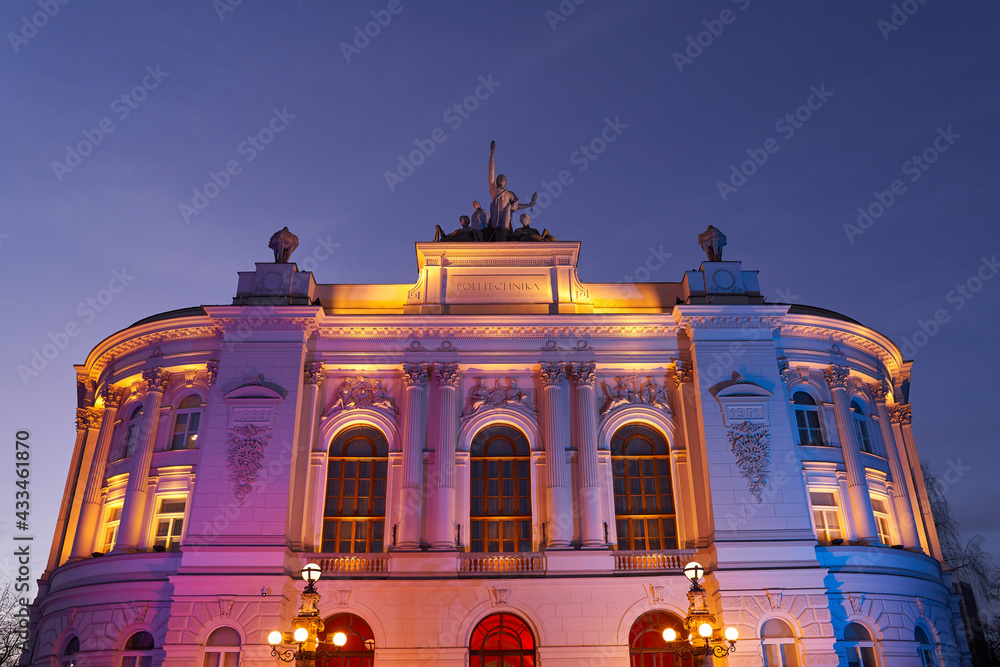 The main building of Warsaw University of Technology at dusk lit by colorful lights. Warsaw, Poland.