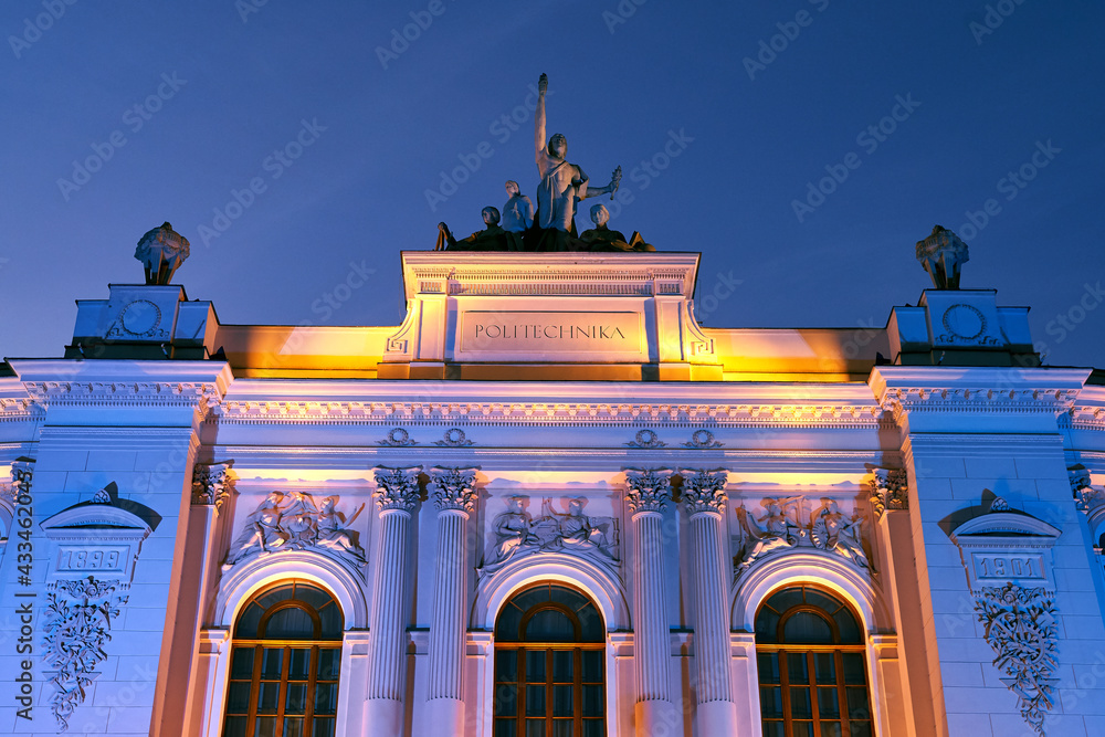 The main building of Warsaw University of Technology at dusk lit by colorful lights. Warsaw, Poland.