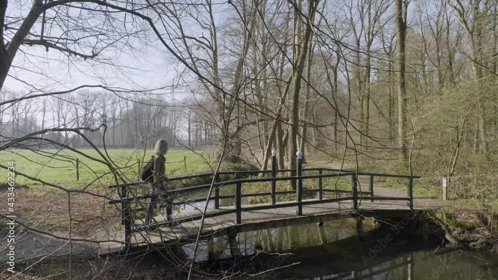 Woman crossing wooden bridge in forest of De Horte estate, Netherlands Woman crossing wooden bridge in forest of De Horte estate, Netherlands