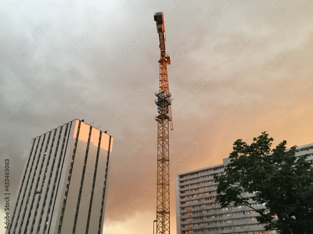 Obraz premium A tower crane and apartment buildings at sunset in Katowice, Poland