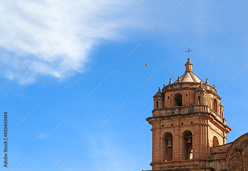 Ornate Bell Tower of Basilica Menor de la Merced against Blue Sky with a Flying Airplane, Cusco, Peru