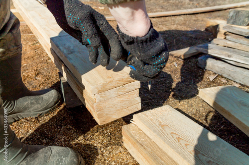 carpenter hands takes measures of wooden boards on construction site photo