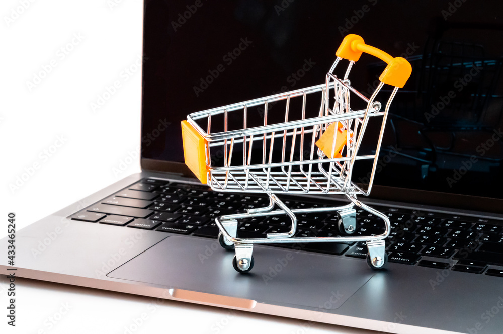 Online shopping concept. Shopping cart on the laptop. Isolated on white background.