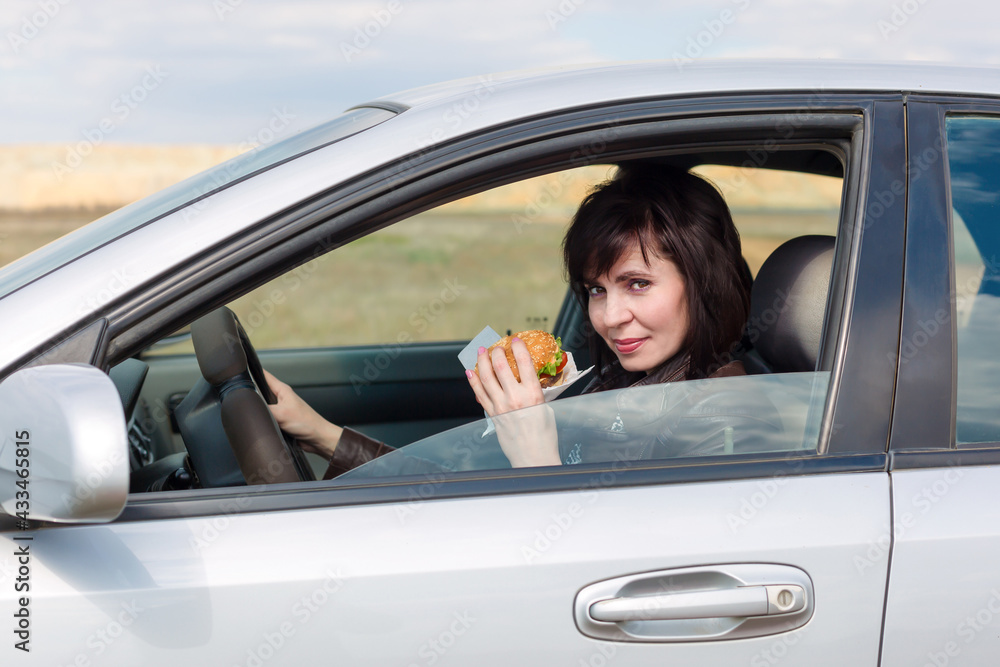 Woman with food in hand driving a car,