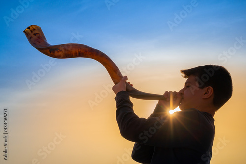 Fototapeta Teen boy blowing Shofar - ram's horn traditionally used for Jewish religious pur