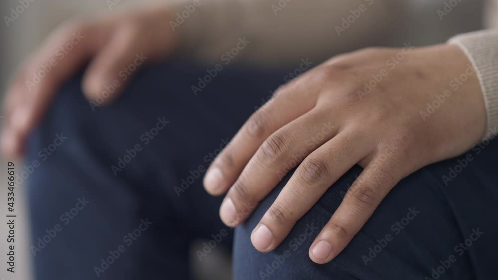 Male African American palms putting on knees in jeans. Unrecognizable young man sitting indoors waiting patiently. Close-up hands Male African American palms putting on knees in jeans. Unrecognizable young man sitting indoors waiting patiently. Close-up hands