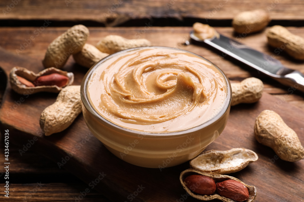 Yummy peanut butter in glass bowl on wooden table, closeup Yummy peanut butter in glass bowl on wooden table, closeup
