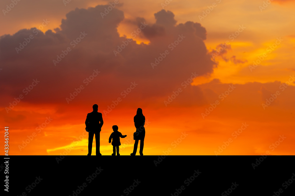 Silhouette of father, mother and daughter walking on the outdoor at dusk, Happy family together, parents with their little child at sunset