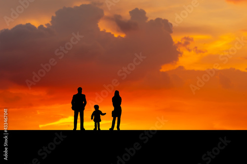 Silhouette of father  mother and daughter walking on the outdoor at dusk  Happy family together  parents with their little child at sunset