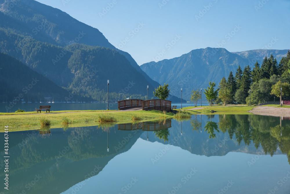 Fototapeta premium morning scenery lake Achensee, calm water with reflection. small bridge.