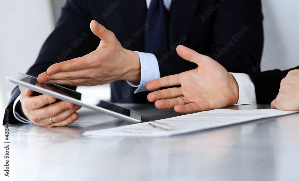 Business people using tablet computer while working together in modern office. Unknown businessman with colleague at workplace. Teamwork and partnership concept Business people using tablet computer while working together in modern office. Unknown businessman with colleague at workplace. Teamwork and partnership concept