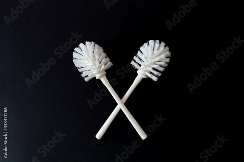 A pair of white toilet brushes on a black background. Copy space. Sanitary cleaning concept photo
