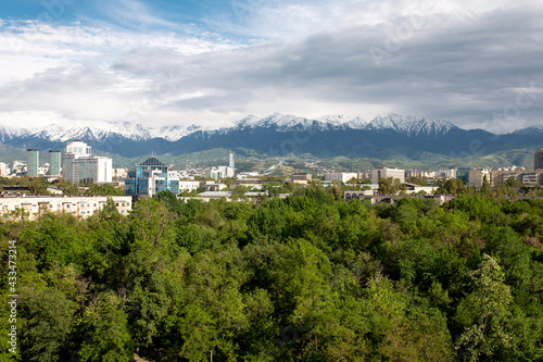 summer city with green trees and blue sky against the backdrop of mountains