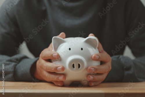 Man hand holding piggy bank on wood table. Save money and financial investment