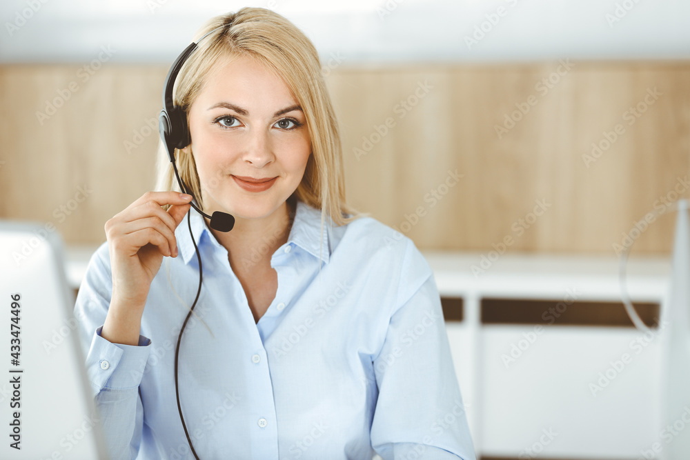 Blonde business woman sitting and communicated by headset in call center office. Concept of telesales business or home office occupation Blonde business woman sitting and communicated by headset in call center office. Concept of telesales business or home office occupation