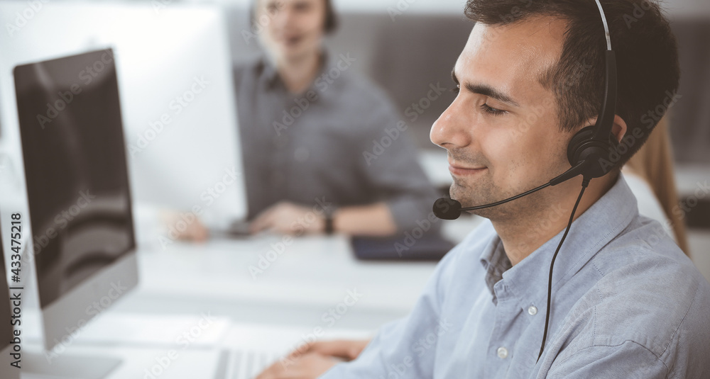 Call center. Group of casual dressed operators at work. Adult businessman in headset at customer service office. Telesales in business Call center. Group of casual dressed operators at work. Adult businessman in headset at customer service office. Telesales in business