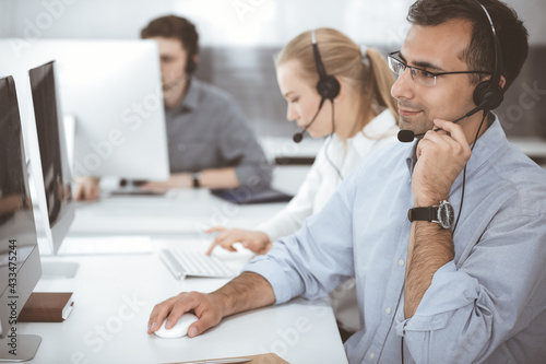 Call center. Group of casual dressed operators at work. Adult businessman in headset at customer service office. Telesales in business