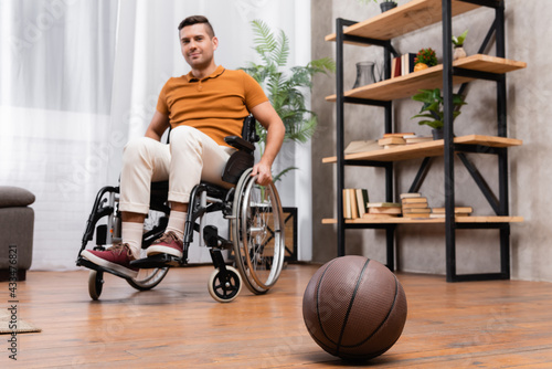 selective focus of basketball near young handicapped man sitting in wheelchair
