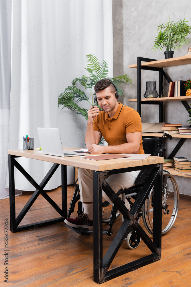 young handicapped man in headset working in home office near laptop young handicapped man in headset working in home office near laptop