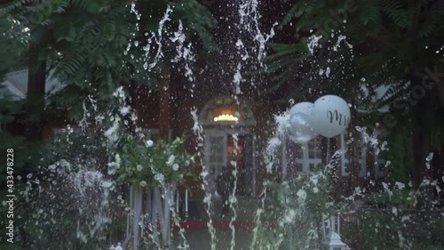 White garden decorative beautiful fountain with blue water. Water splashes, outdoor party. photo