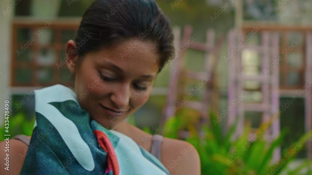 Young European brunette girl wipes a towel in the backyard with a green garden Young European brunette girl wipes a towel in the backyard with a green garden