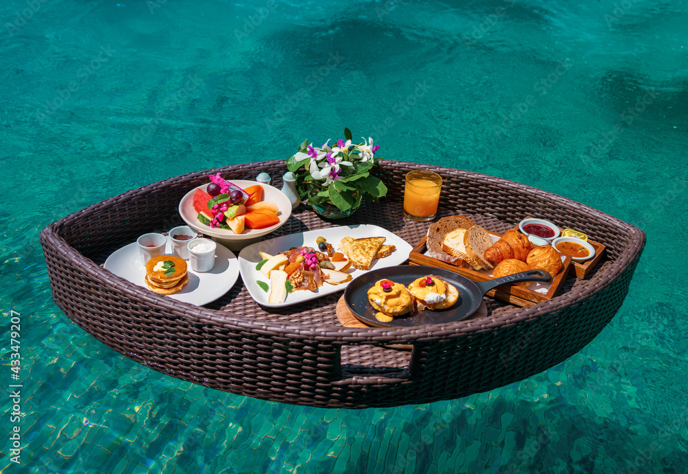 Set of floating breakfast tray in swimming pool with fried egg omelette